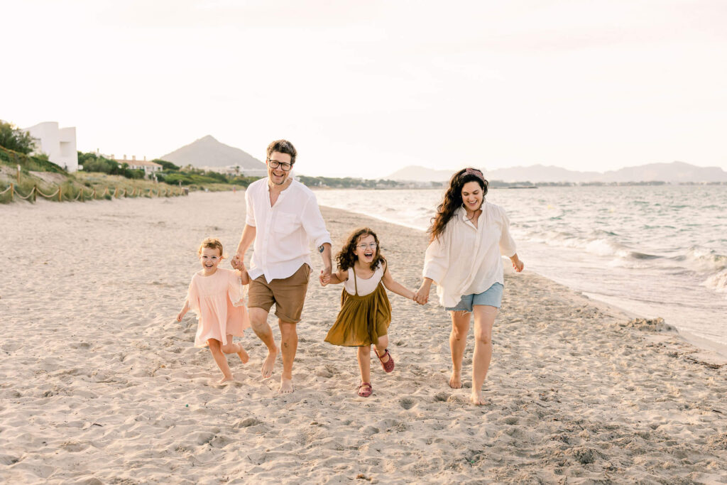 Family walking hand in hand on the beach in Mallorca during a relaxed outdoor photoshoot.