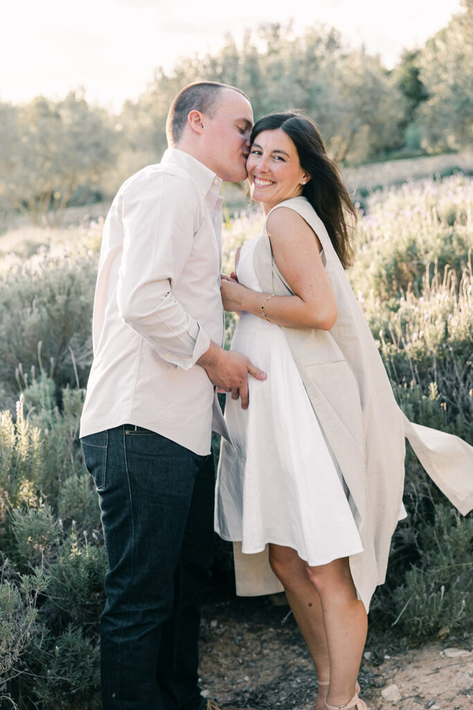 Expecting couple embracing lovingly in the lavender fields of Finca Serena, Mallorca, during a romantic and natural maternity session.